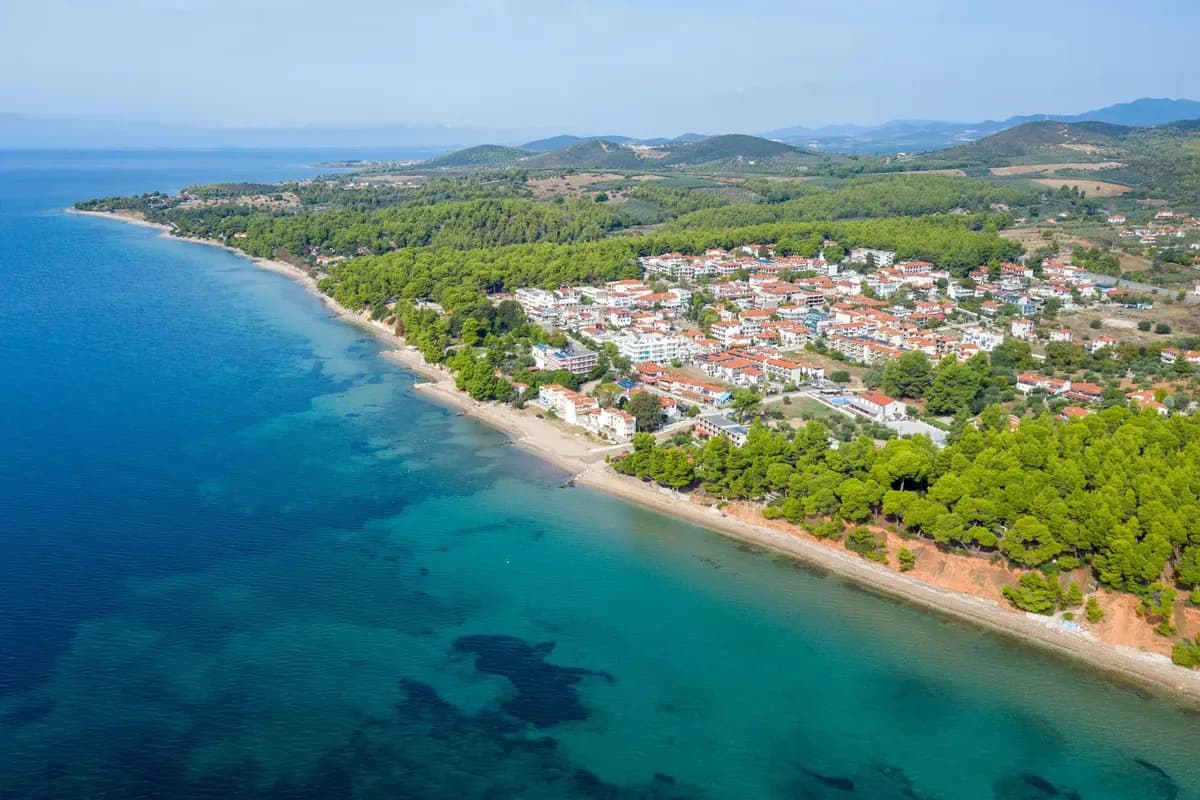 Wybrzeże półwyspu Sithonia na Chalkidiki z lotu ptaka: miejscowość Metamorfosis wśród sosen, wąska plaża i turkusowa płycizna