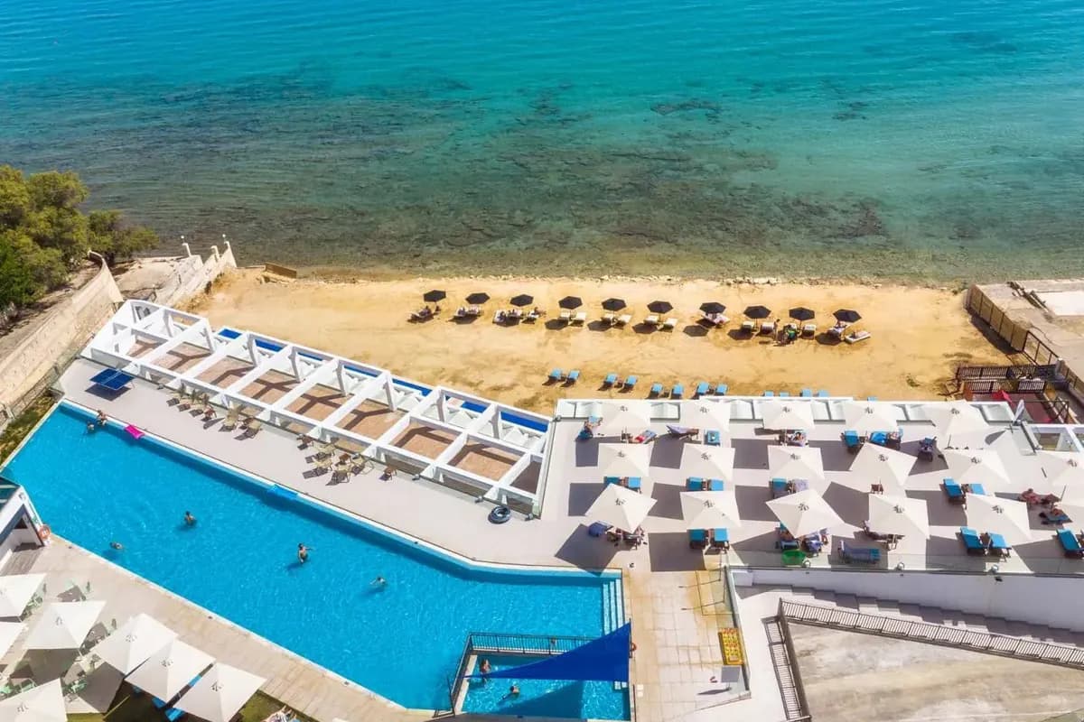 Hotelowy basen nad piaszczystą plażą w Kipseli na Zakynthos, z parasolami i turkusowym, przejrzystym morzem