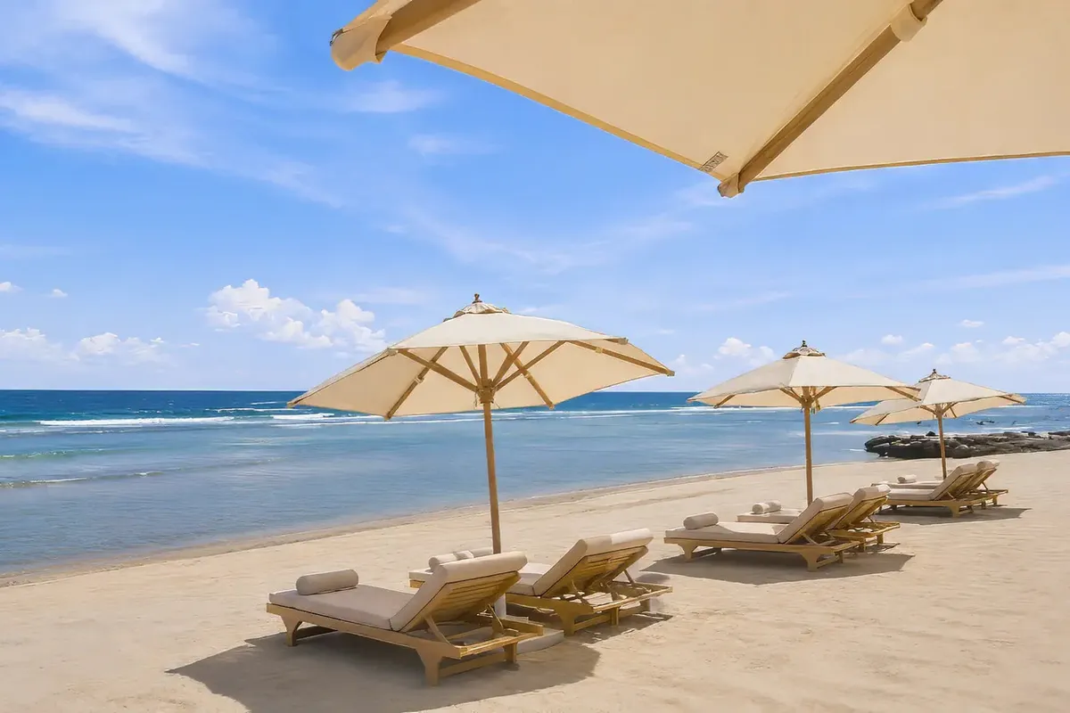 Drewniane leżaki i jasne parasole na piaszczystej plaży przy hotelu Cleopatra Signature w Marsa Alam