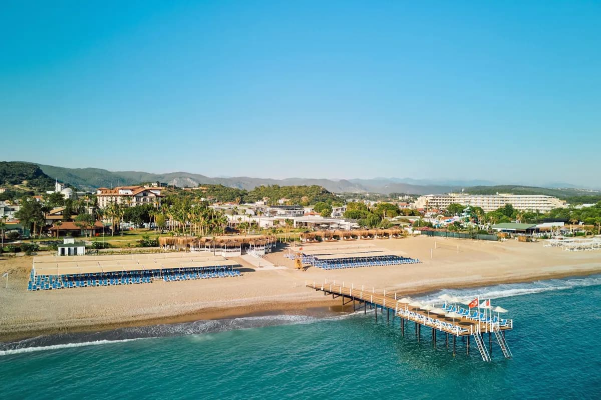Plaża hotelu Selectum Colours Side na Riwierze Tureckiej z lotu ptaka: drewniane molo z leżakami, turkusowe morze i góry Taurus w tle