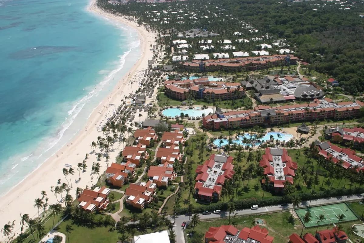 Widok z lotu ptaka na hotel Caribe Deluxe Princess przy plaży Bávaro na Dominikanie: budynki z czerwonymi dachami, baseny, palmy i turkusowe morze