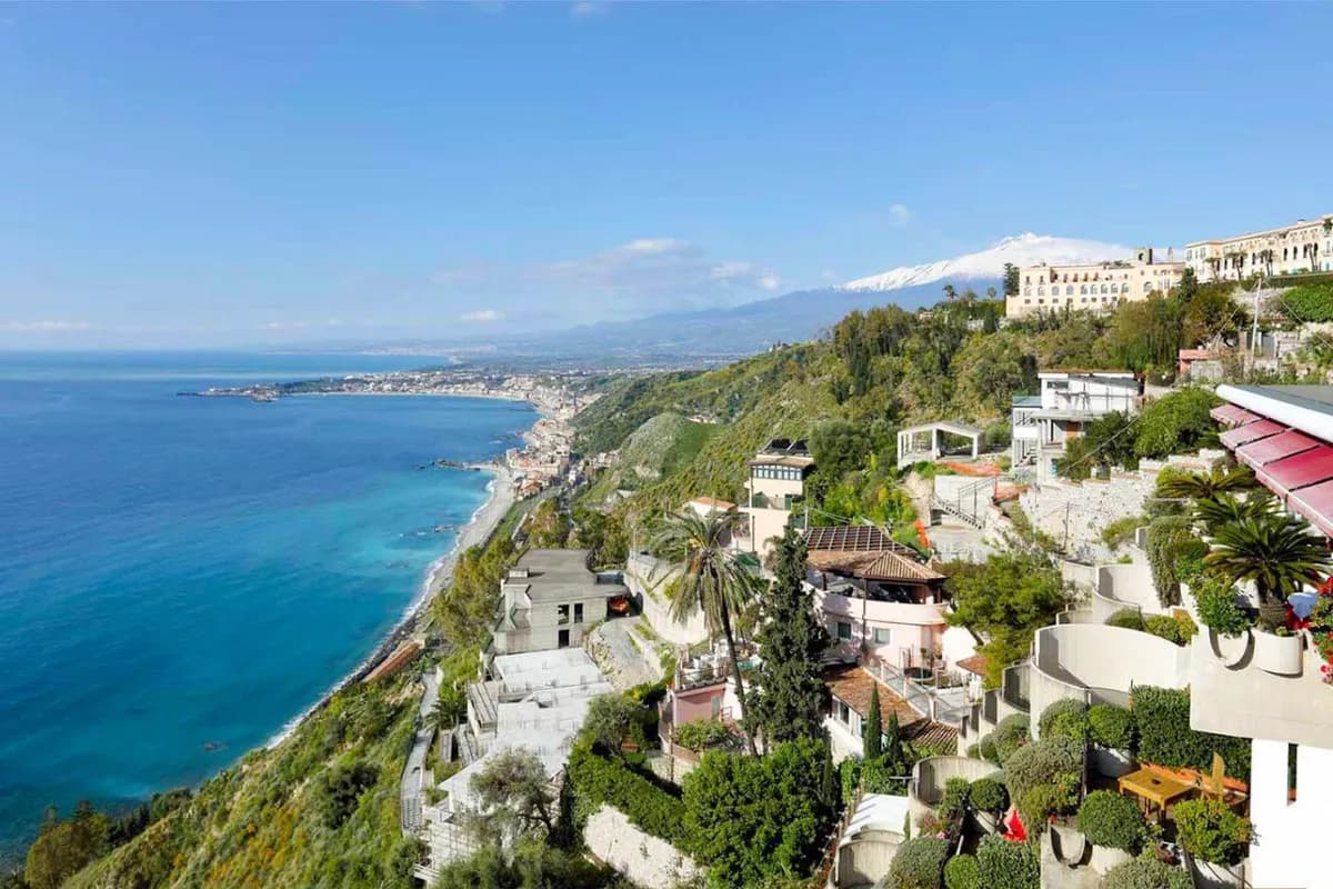 Zbocze Taorminy z hotelami i ogrodami nad Morzem Jońskim, w dali zatoka Giardini Naxos i ośnieżony szczyt Etny