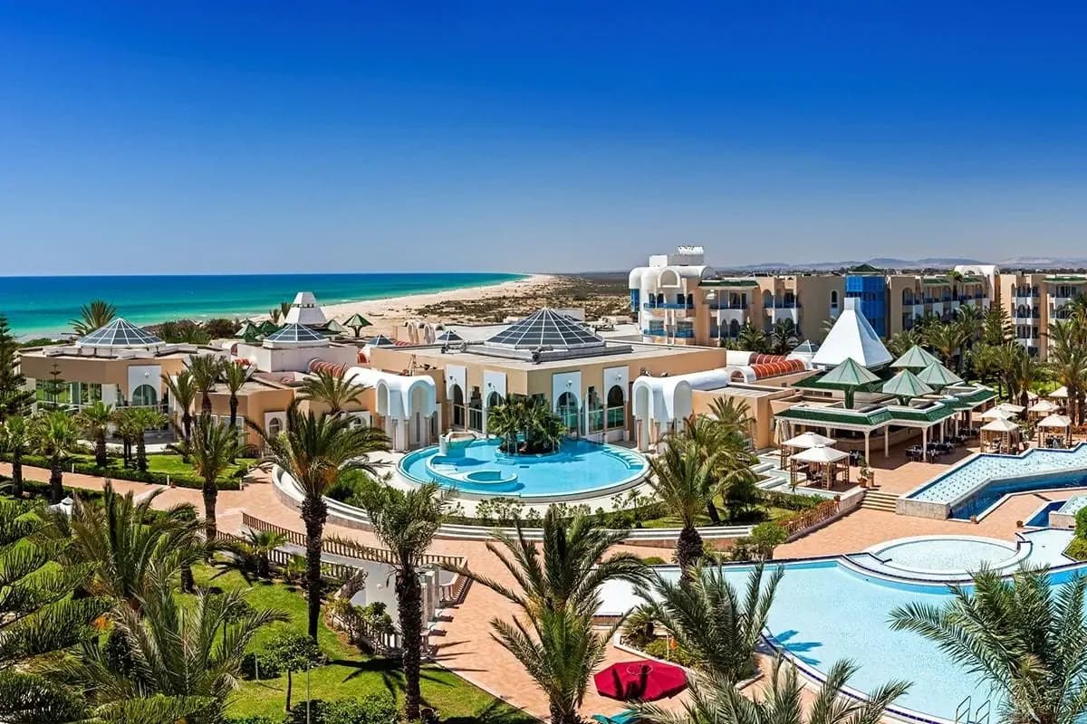 Hotel Hasdrubal Thalassa w Yasmine Hammamet z góry: baseny wśród palm, przeszklone dachy w kształcie piramid i długa piaszczysta plaża nad turkusowym morzem