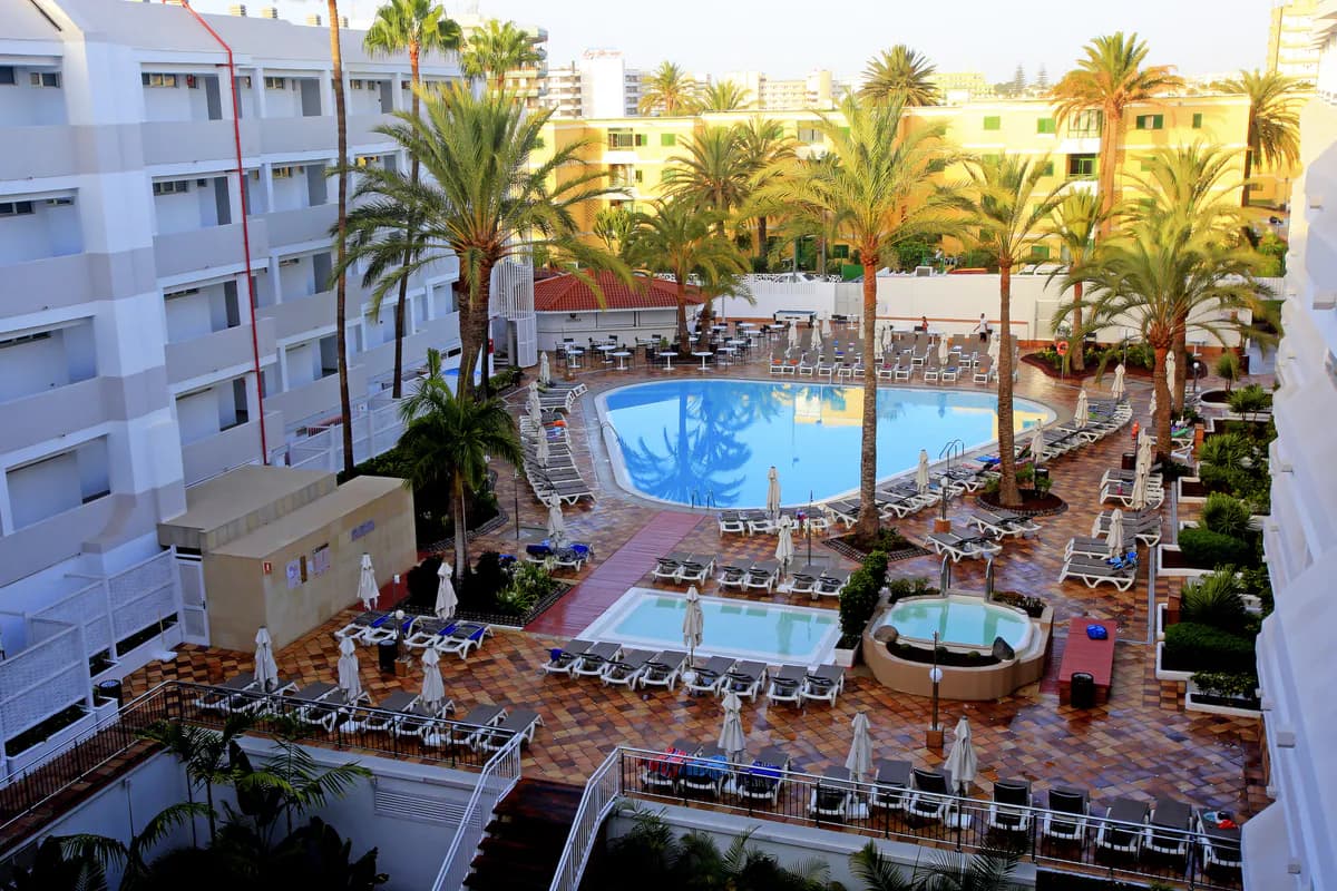 Dziedziniec hotelu Labranda Bronze Playa na Gran Canarii z góry: basen wśród palm, rzędy leżaków i złożone parasole w porannym słońcu