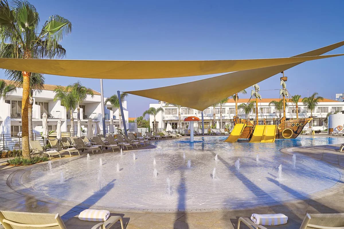 Brodzik dla dzieci w hotelu Olympic Lagoon Resort w Ayia Napie: tryskające fontanny, statek piracki z żółtymi zjeżdżalniami i żagle dające cień