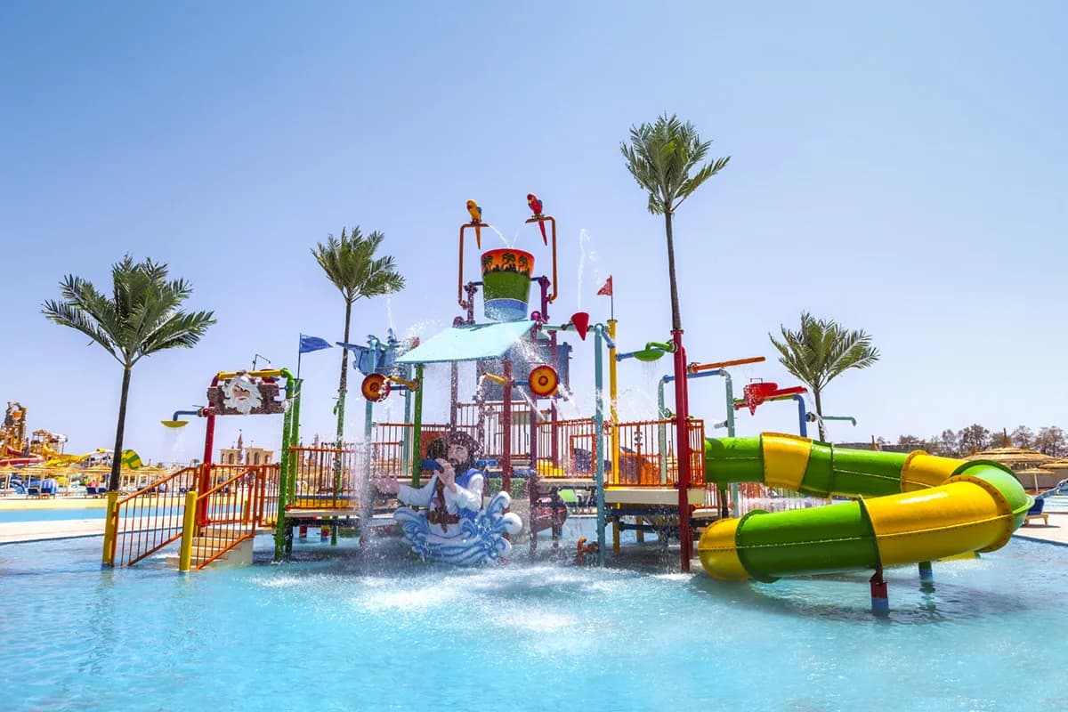 Wodny plac zabaw z fontannami i zielono-żółtą zjeżdżalnią w płytkim basenie aquaparku dla dzieci w hotelu Pickalbatros Aqua Park w Szarm el-Szejk