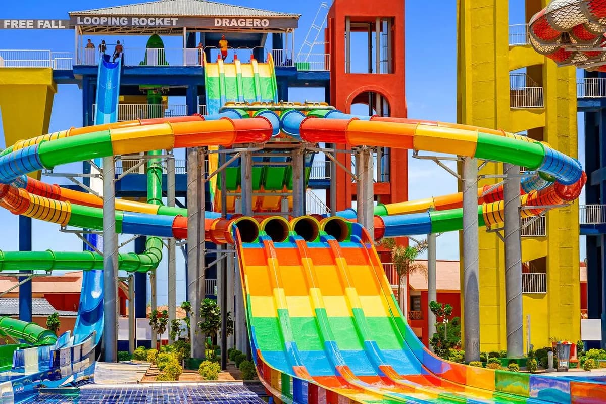 Kolorowe zjeżdżalnie wodne w aquaparku hotelu Pickalbatros Jungle Aqua Park w Hurghadzie, z szeroką zjeżdżalnią w barwach tęczy na pierwszym planie
