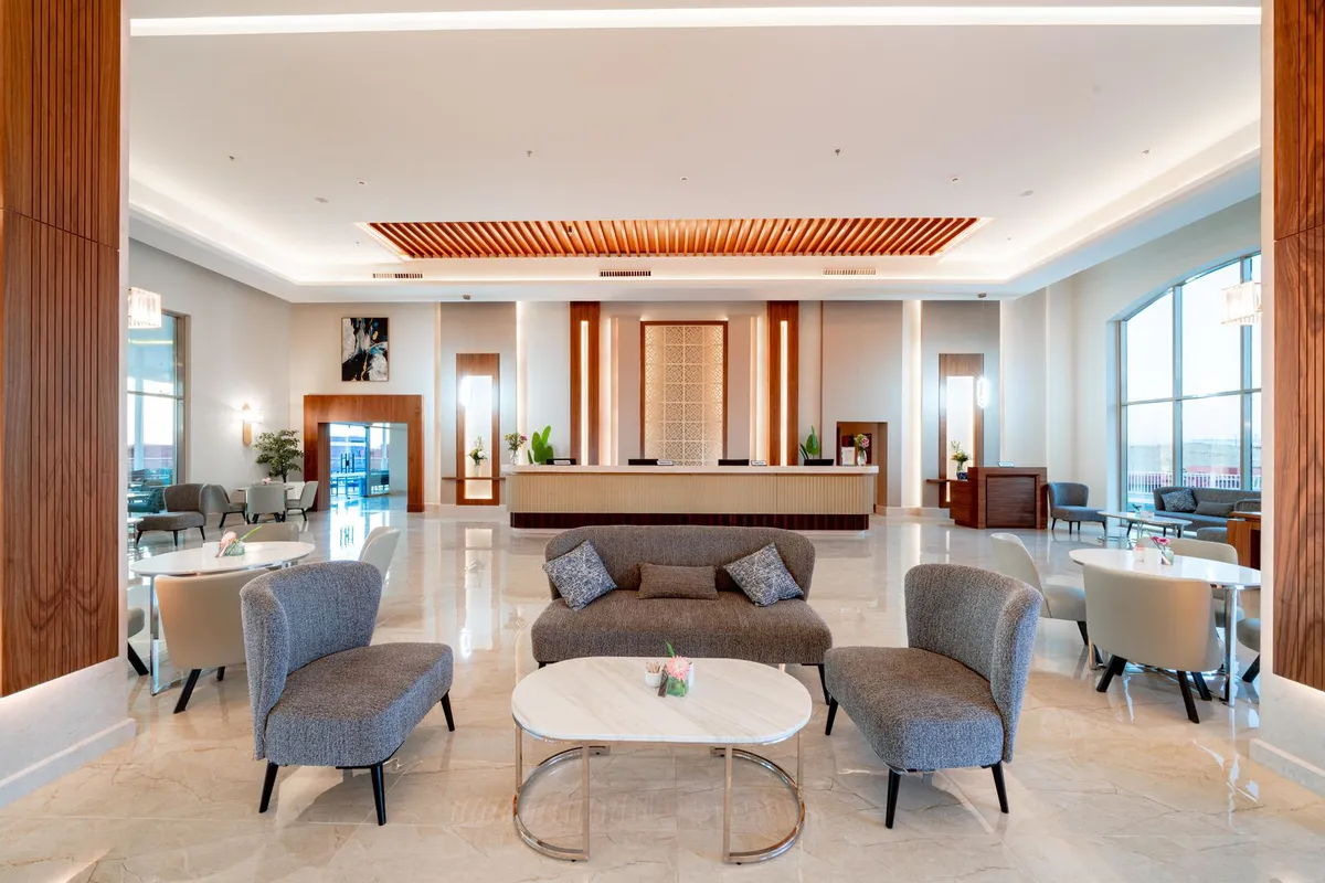 Przestronne lobby hotelu Pickalbatros Vita Resort Portofino w Marsa Alam: szare fotele i sofa przy stoliku, w głębi recepcja